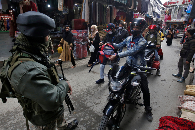 A man on a motorbike shows his belongings to an Indian security force personnel during a cordon and search operation, in Srinagar